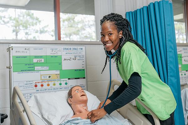 A nursing student works on a mannequin